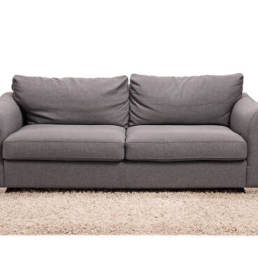 Studio shot of a grey sofa on a carpet isolated on white background